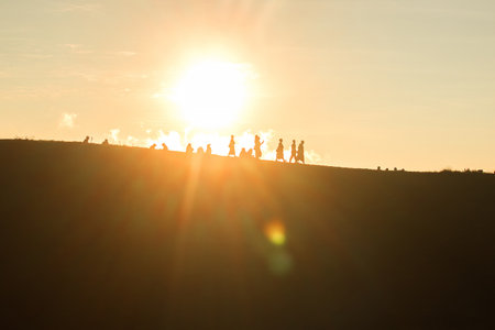 Travelers silhouettes against the orange light of sunset on the mountains.の写真素材