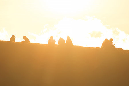 Travelers silhouettes against the orange light of sunset on the mountains.の写真素材