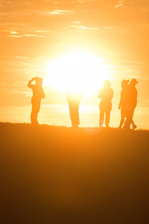 Travelers silhouettes against the orange light of sunset on the mountains.の写真素材