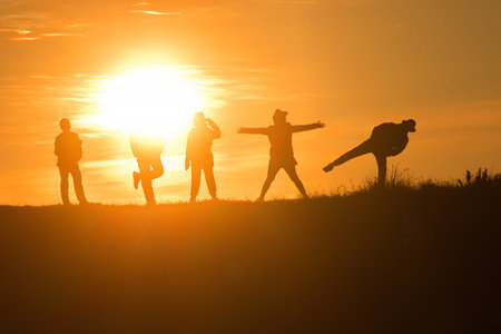Travelers silhouettes against the orange light of sunset on the mountains.の写真素材