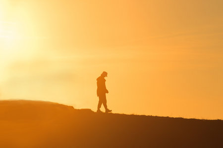 Travelers silhouettes against the orange light of sunset on the mountains.の写真素材