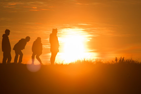 Travelers silhouettes against the orange light of sunset on the mountains.の写真素材