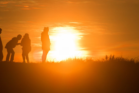 Travelers silhouettes against the orange light of sunset on the mountains.の写真素材