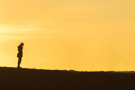 Travelers silhouettes against the orange light of sunset on the mountains.の写真素材