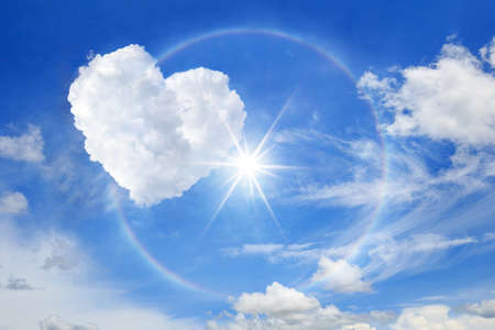 Sun halo with heart cloud on the blue sky, Cloud shaped heart on blue sky white cloud background.の写真素材