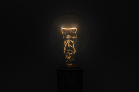 A photo of incandescent light bulb light up in the dark.の写真素材
