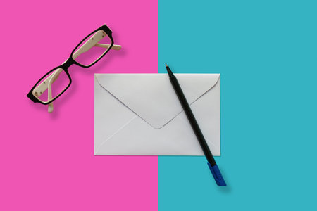 Letter envelop with pen and eye glesses on pink and blue background