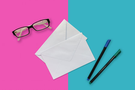Letter envelop with pen and eye glesses on pink and blue background