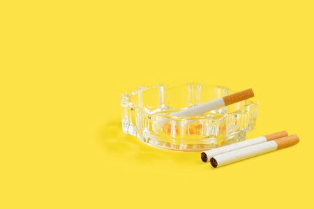 Photo of cigarette and ashtray on yellow backgroundの写真素材