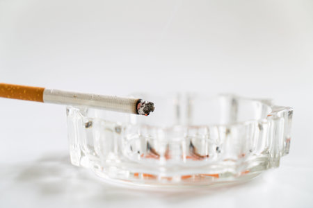 Burnt cigarette on the glass ashtray isolated on the white background