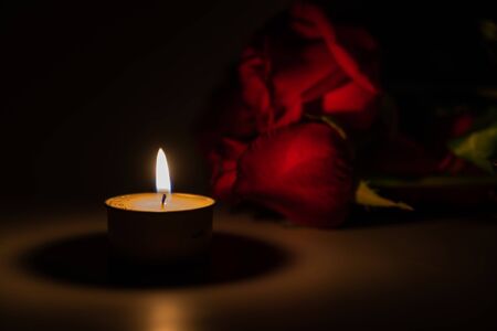 tealight candle and red rose at midnight timeの写真素材