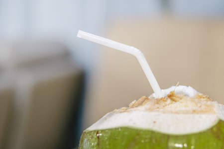 A green coconut with drinking straw