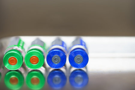 Four vaccine bottles lie on the stainless steel tray. By focusing on the bottle caps that are rubber...