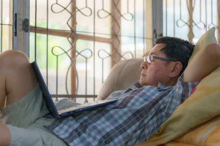 An elderly man falls asleep while using a laptop