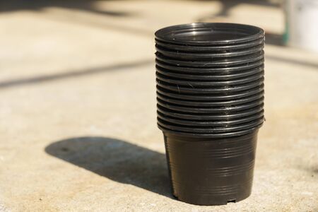 Black plastic pots on the cement floor in the sun.の写真素材