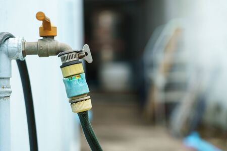 Hoses that connect to the faucet with an old connector at the back of the houseの写真素材