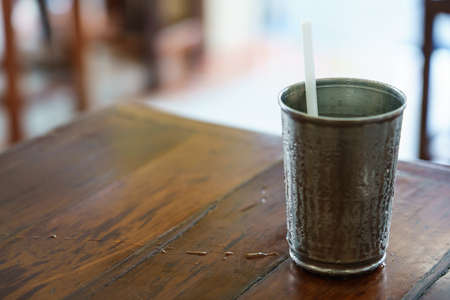 The white drinking straw in a metal glass that has cold water until steam condenses on the side of the glass.の写真素材