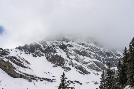 Mountain peak in winter covered with snow and cloudsの写真素材
