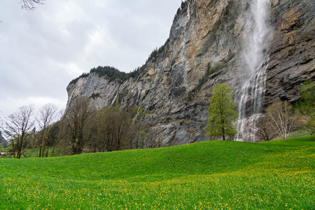 Landscape photo of the Staubbach Falls, sky, lawn and trees.の写真素材