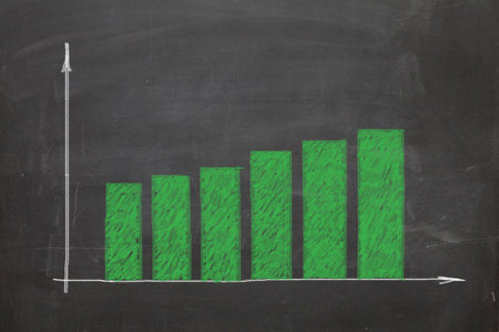 The price is rising up. Growing graph with big green business candles on blackboard painting chalk....