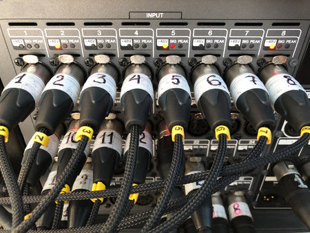 Microphone sound cables connected to the signal audio console on the stage. Plugged XLR cables.