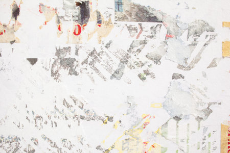 Closeup torn and peeling old paper ads on billboard with traces of glue.
