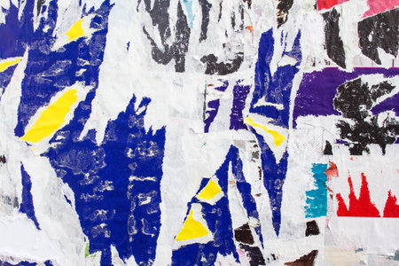 Dirty torn and peeling paper posters on a wall. Grungy street billboard with old motley placards...
