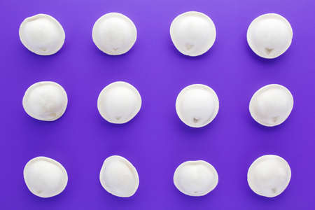 Uncooked frozen dumplings on purple background. Russian pelmeni. Ravioli. Flat lay.の写真素材