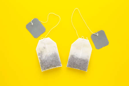 Two tea bags with gray blank label on yellow background.の写真素材