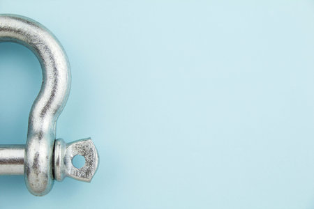 Half of steel metal rigging shackles on blue background with space for text.の写真素材