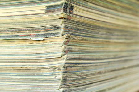 Stack of old magazines. Shabby paper magazines. Side view with bokeh effect.の写真素材