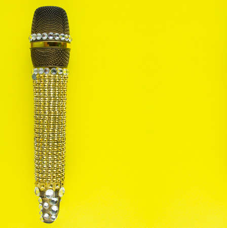 Professional vocal radio microphone decorated with bright shiny and glittering gold rhinestones on yellow background. Space for text.の写真素材