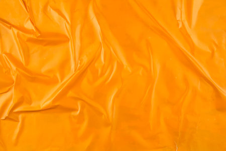 Crumpled glossy orange magazine paper poster background.