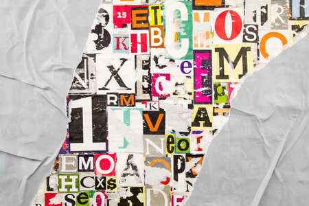 Torn and crumpled gray paper on colorful abstract collage from clippings with letters and numbers. Creative background.の写真素材