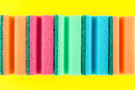 Set of colorful soft sponges or scouring pads for washing and cleaning on yellow background.の写真素材