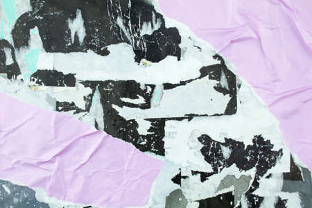 Torn black and purple posters glued on billboard with old dirty peeling paper. Abstract and creative background of ripped magazine paper.の写真素材