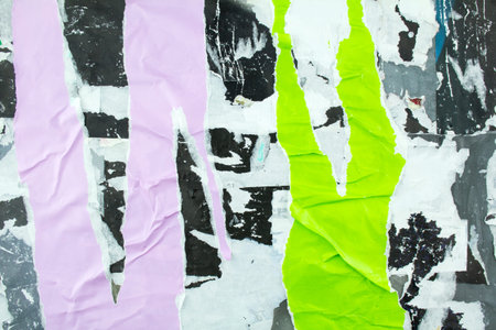 Torn and crumpled purple and green posters glued on billboard with old dirty paper. Abstract and...