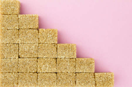 Brown sugar cubes on pink paper background. Top view.の写真素材