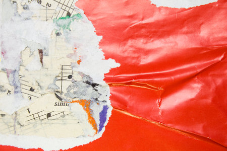 Torn and crumpled glossy red poster on old scraps of paper music sheet with notes background.の写真素材