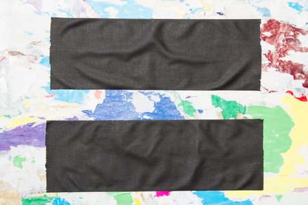 Two black crumpled pieces of cloth gaffer tape on billboard with torn colorful paper posters...