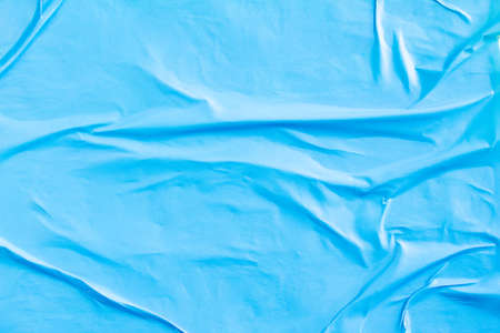 Blue crumpled creased paper placard poster glued on billboard background.の写真素材