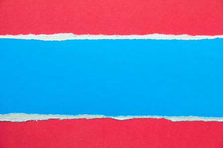 Blue torn piece of cardboard on red paper texture background. Copy space for text message.の写真素材