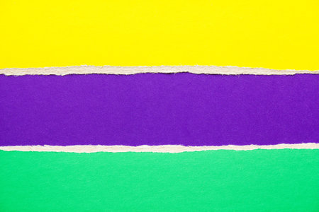 Purple, green and yellow torn cardboard paper background with copy space for text message.