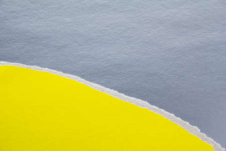 Yellow torn piece of cardboard on silver gray sheet of paper texture background. Can be used for text.の写真素材