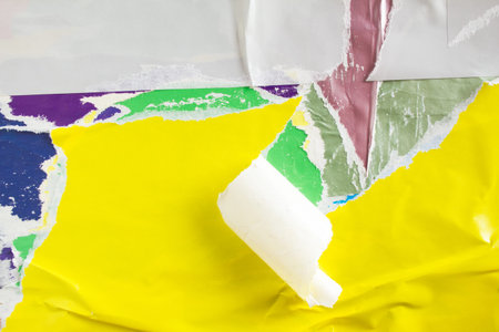 Yellow crumpled, torn and peeling paper placard on urban street billboard background.
