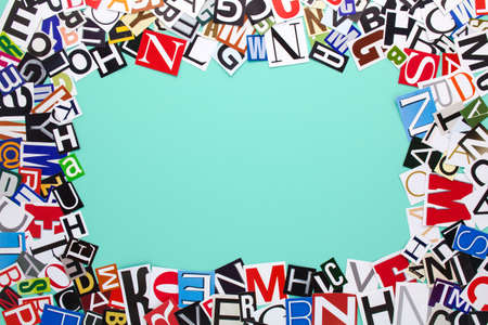 Alphabet letters cutting from paper magazine on azure green background with copy space for text. Colorful abstract collage from clippings with newspaper magazine letters.の写真素材