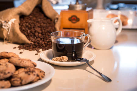 Cup of coffee and cookies with coffee beans in jute bag and grinderの写真素材