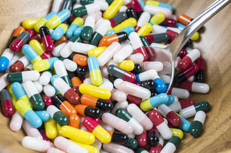 Pills in a cereal bowl with spoonの写真素材