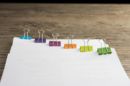 Multiclored paper binders on paperwork close up