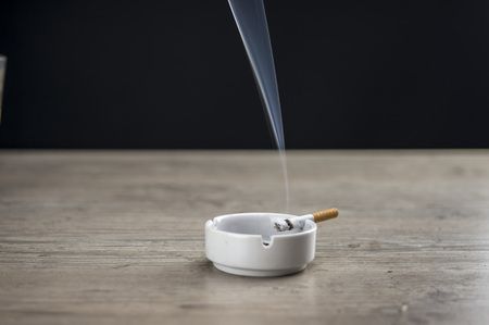 Lit cigarette burning in ashtray close upの写真素材